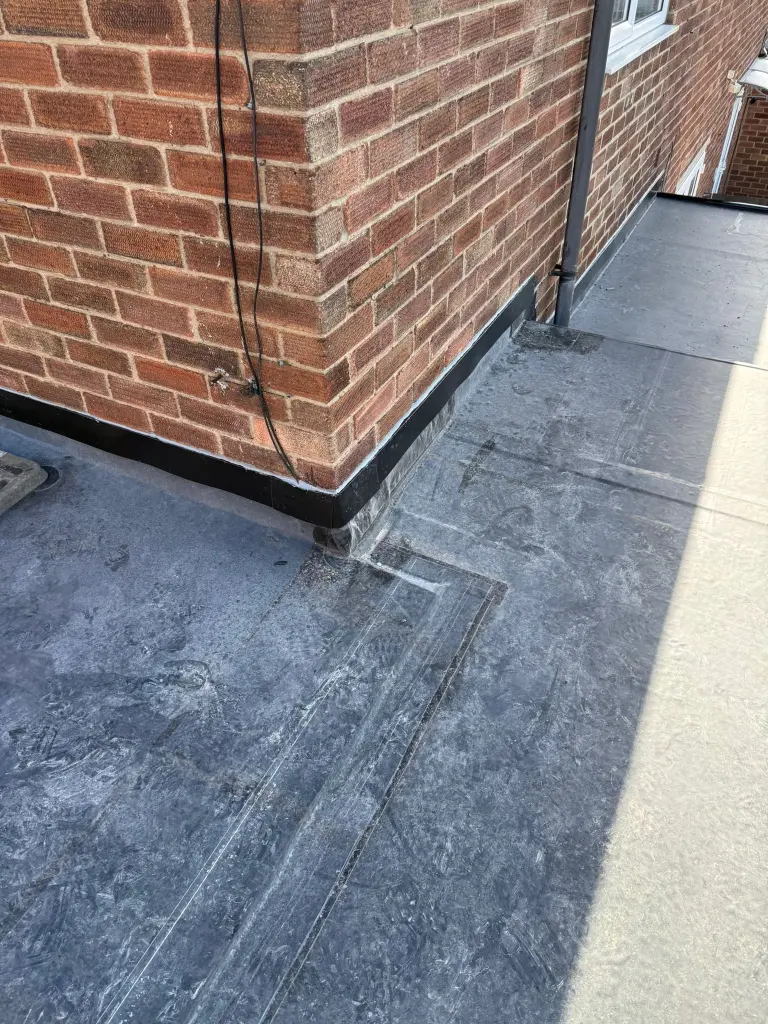 Flat roof membrane against a brick wall